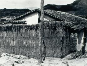Choza con cerca de vara y montañas. Impresión de negativo original del Comitato Tina Modotti. Trieste, Italia.