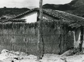 Choza con cerca de vara y montañas. Impresión de negativo donado por Vittorio Vidali. Fototeca INAH